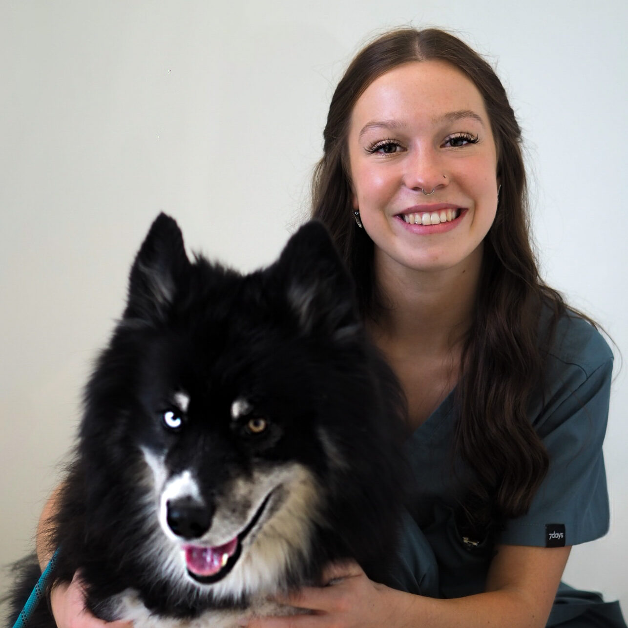 Portraitbild der TFA Emily Herrmann, die lächelnd neben einem Hund sitzt.